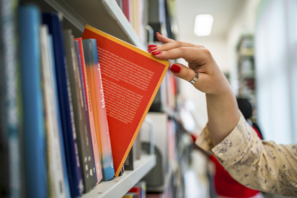 selecting a book from the library bookshelf