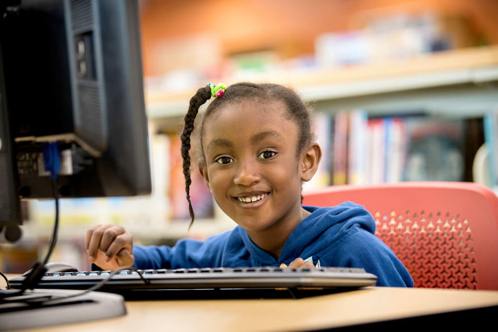 girl at Pratt Library computer, smiling