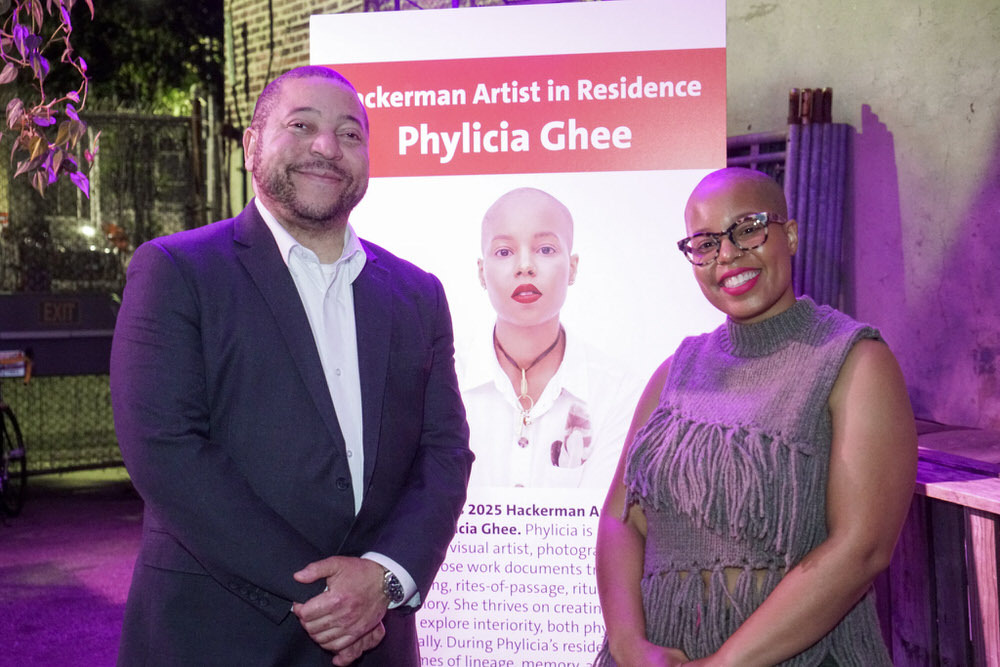 Chad Helton and Phylicia Ghee smiling by Artist in Residence sign